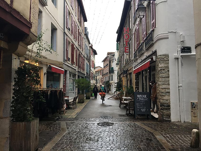A bicyclist passes through a narrow old-town street in France.