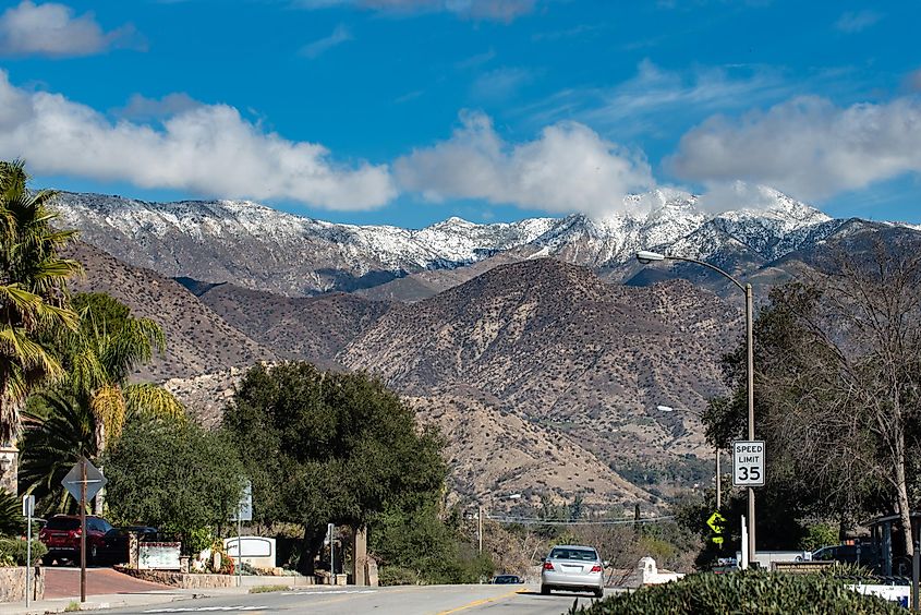 Chiefs Peak Mountain over Ojai, California is covered in snow and low clouds while overlooking highway 33 traveled by cars