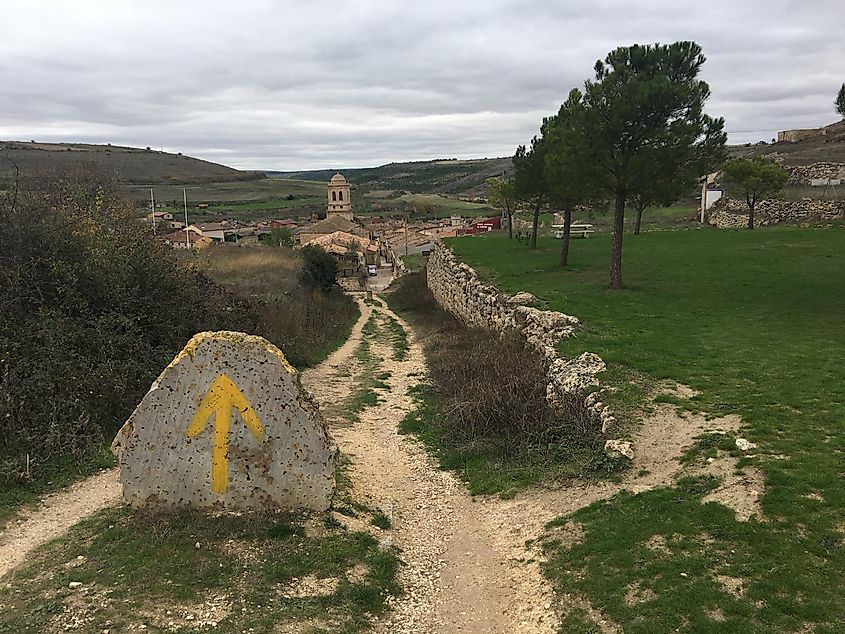 A yellow arrow painted on a stone points the way to a small Spanish village in the middle of the prairies. 
